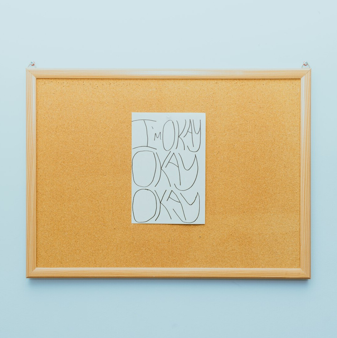 Notebook with handwritten notes and red string pinned on a corkboard